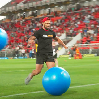 Man kicking gym ball on soccer field