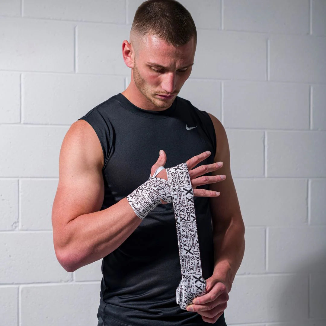 Man wrapping his wrist with a black and white Xpeed Hand Wraps