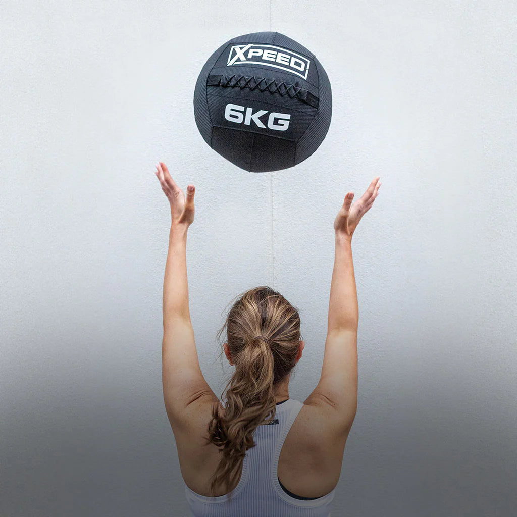 Woman throwing a 6kg Xpeed exercise ball into the air