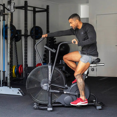 Man training on an air elliptical in personal garage gym.